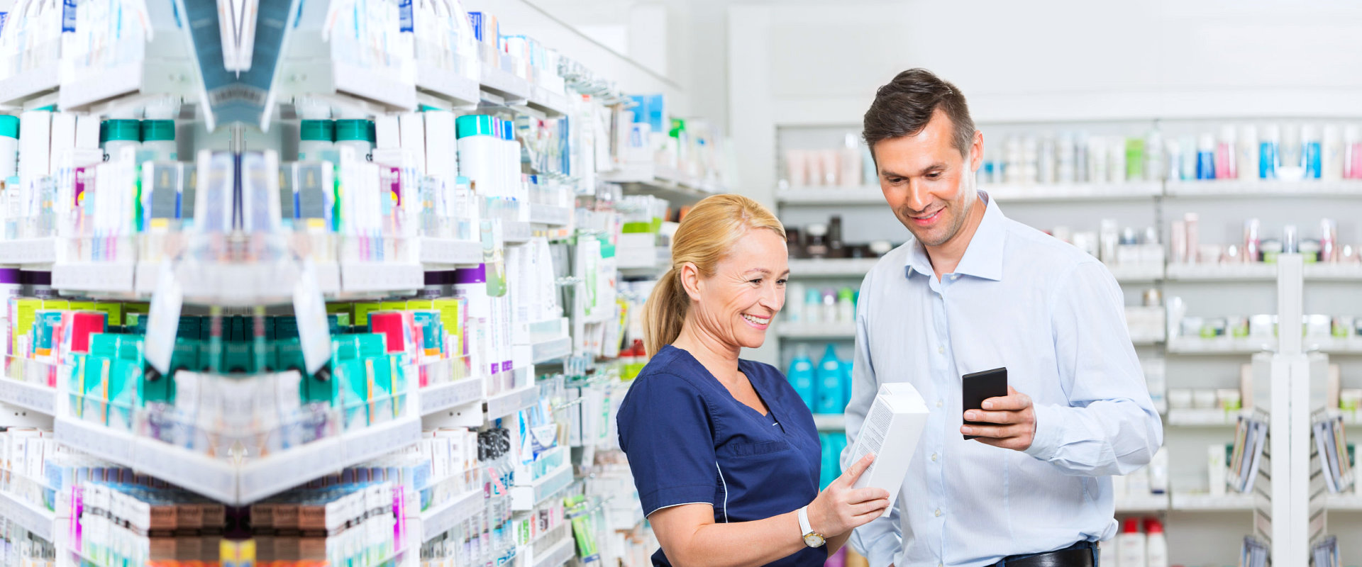 Smiling male customer using mobile phone and a pharmacist